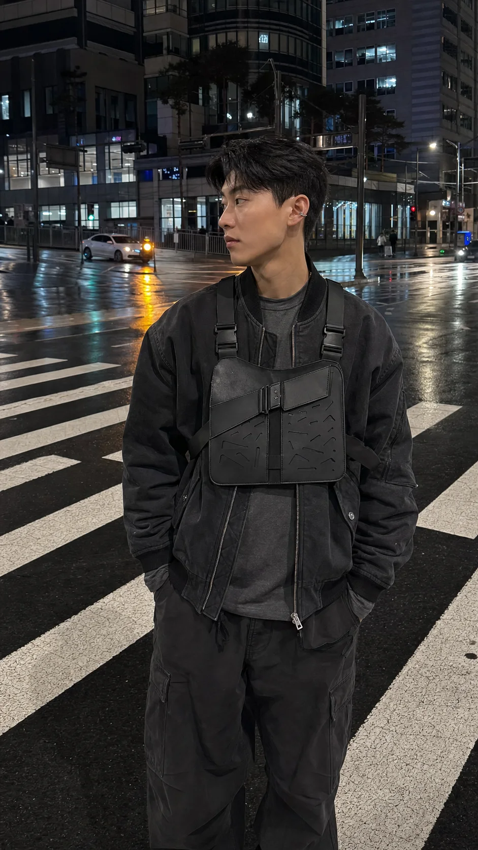 Seoul rainy crosswalk styling image showing the Clothixpack CXP-A104 Orbit Chest Rig over a washed black bomber with charcoal cargo pants.