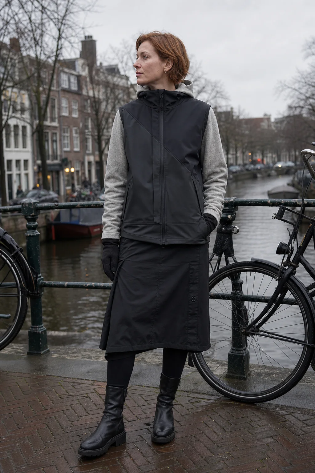 Amsterdam canal bridge styling image showing the Clothixpack CXP-A106 Kilo Waterproof Vest over a grey hoodie with a black technical skirt.