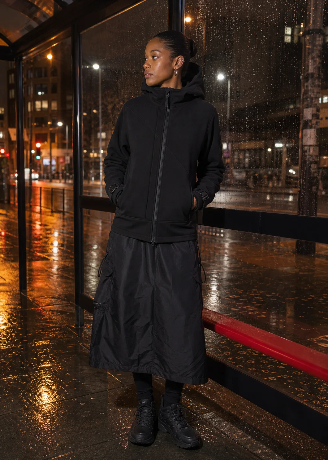 London bus stop styling image showing the Clothixpack CXP-H102 Signal Technical Hoodie with a black waterproof maxi skirt.